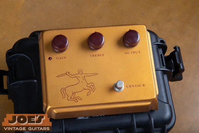 The gold top face of an original Klon Centaur professional overdrive showing the Gain, Treble, and Output knobs and the red centaur archer graphic.
